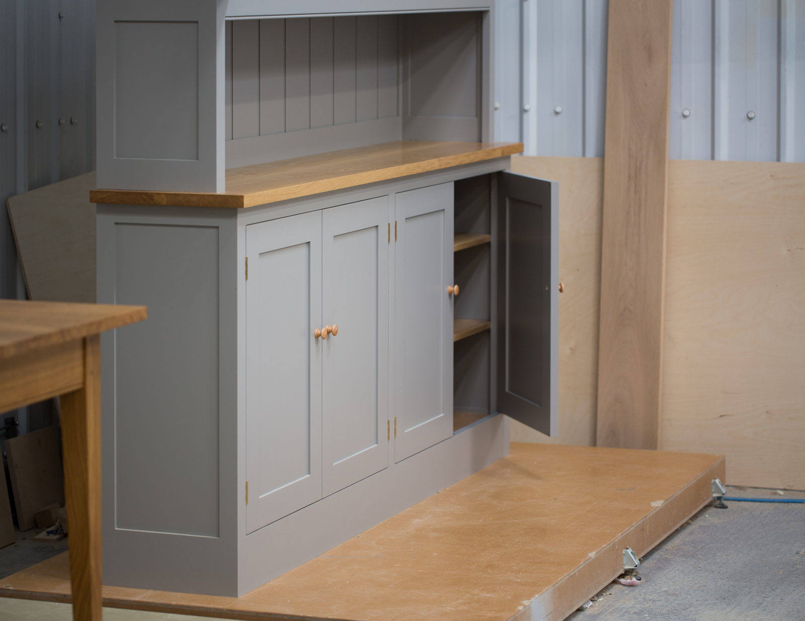 Dresser handpainted in Farrow & Ball Estate Egshell - 'Worsted'. Tulip wood frame with birch ply panels. Oak veneered and lipped birch ply shelves. Hand-turned hardwood knobs. Traditional brass butt hinges with bespoke soft close function. Adjustable 'hidden' levelling feet.