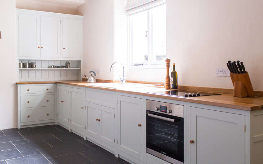 Shaker style kitchen. Birch plywood cabinets with hand painted hardwood frames (Farrow and Ball Estate Eggshell, Pale Powder).Traditional inset sink and integral dishwasher. Inset cooker hob and integral oven. 4.5m full stave oak worktop with upstand. Solid brass hinges and adjustable brass shelf supports. Solid oak dovetailed drawers with painted hardwood fronts. Hand turned beech knobs.