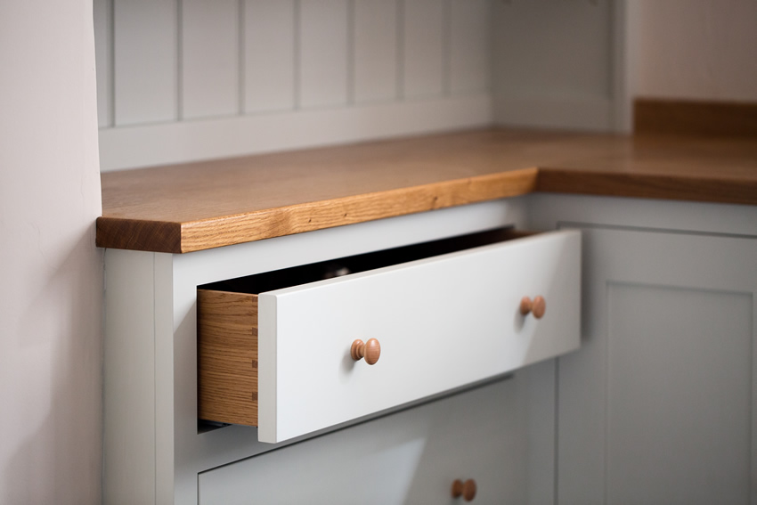 Shaker style kitchen. Birch plywood cabinets with hand painted hardwood frames (Farrow and Ball Estate Eggshell, Pale Powder).Traditional inset sink and integral dishwasher. Inset cooker hob and integral oven. 4.5m full stave oak worktop with upstand. Solid brass hinges and adjustable brass shelf supports. Solid oak dovetailed drawers with painted hardwood fronts. Hand turned beech knobs.