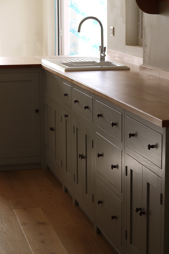 Shaker style kitchen. Birch plywood cabinets with hand painted hardwood frames (Farrow and Ball, Lamp Room Gray). Sink area with integral dishwasher, traditional ceramic inset sink and full stave beech top and upstand. Dovetailed drawers made of solid beech with painted hardwood fronts and walnut hand turned knobs.