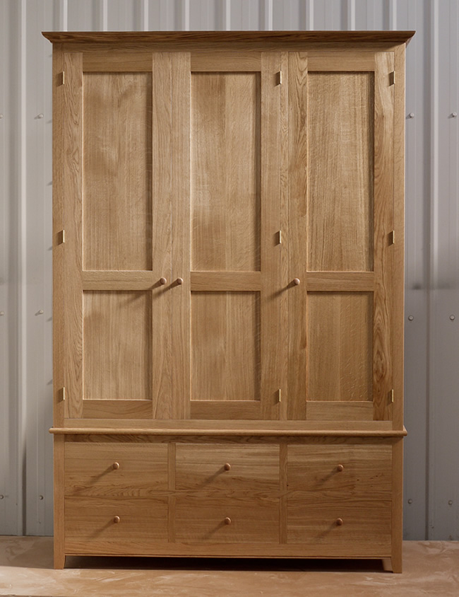 Oak wardrobe with solid oak carcass and panels. Oak faced birch ply shelves. Dovetailed oak drawers on high quality soft close runners. Bespoke cornice in solid oak and hand turned oak knobs. Solid brass hinges and adjustable shelf supports.