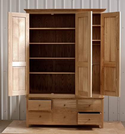 Oak wardrobe with solid oak carcass and panels. Oak faced birch ply shelves. Dovetailed oak drawers on high quality soft close runners. Bespoke cornice in solid oak and hand turned oak knobs. Solid brass hinges and adjustable shelf supports.